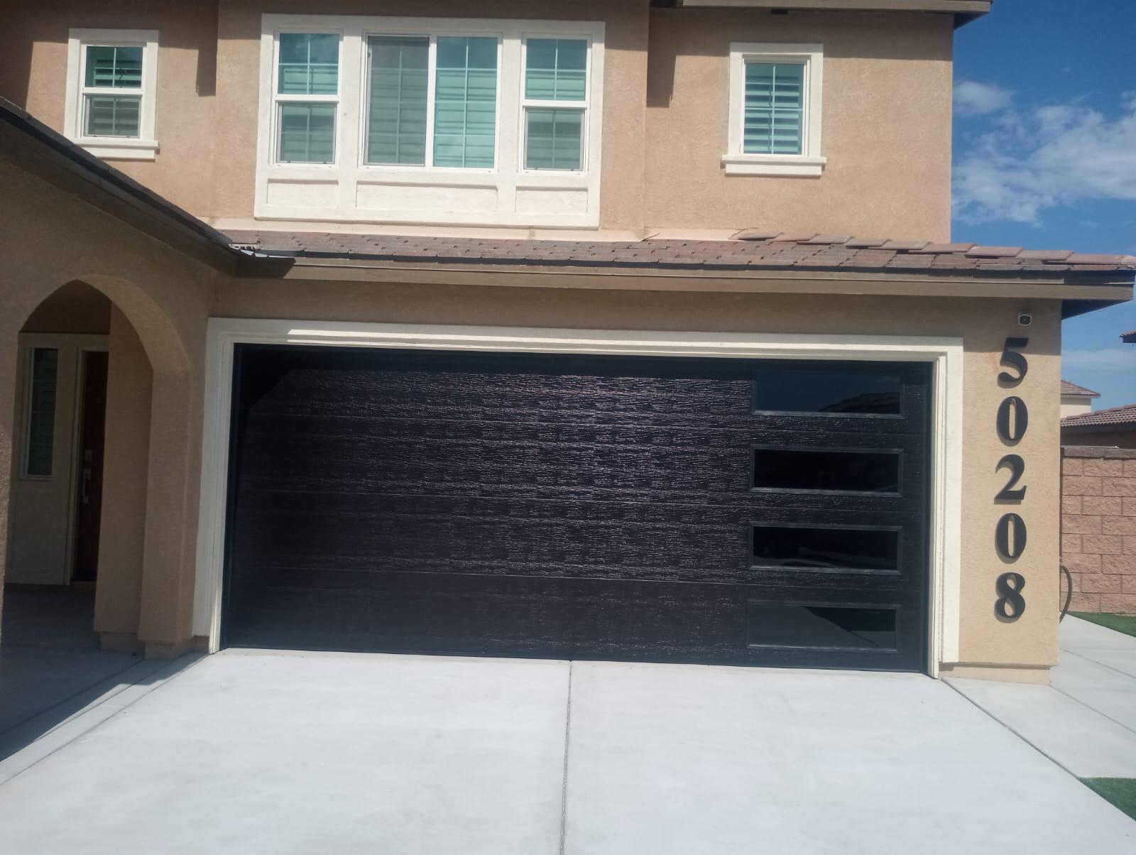 Modern dark woodgrain garage door with vertical glass panels in Palm Springs