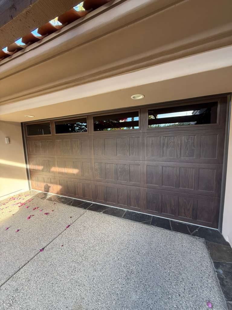 Walnut woodgrain garage door with window inserts in Indian Wells